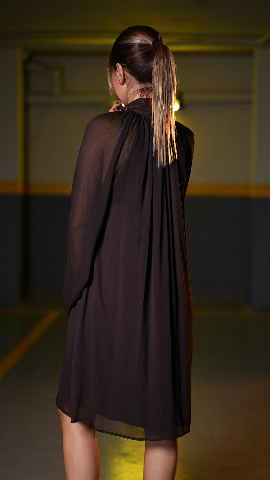 Back view of dark chocolate-brown dress with transparent sleeves and flowing silhouette