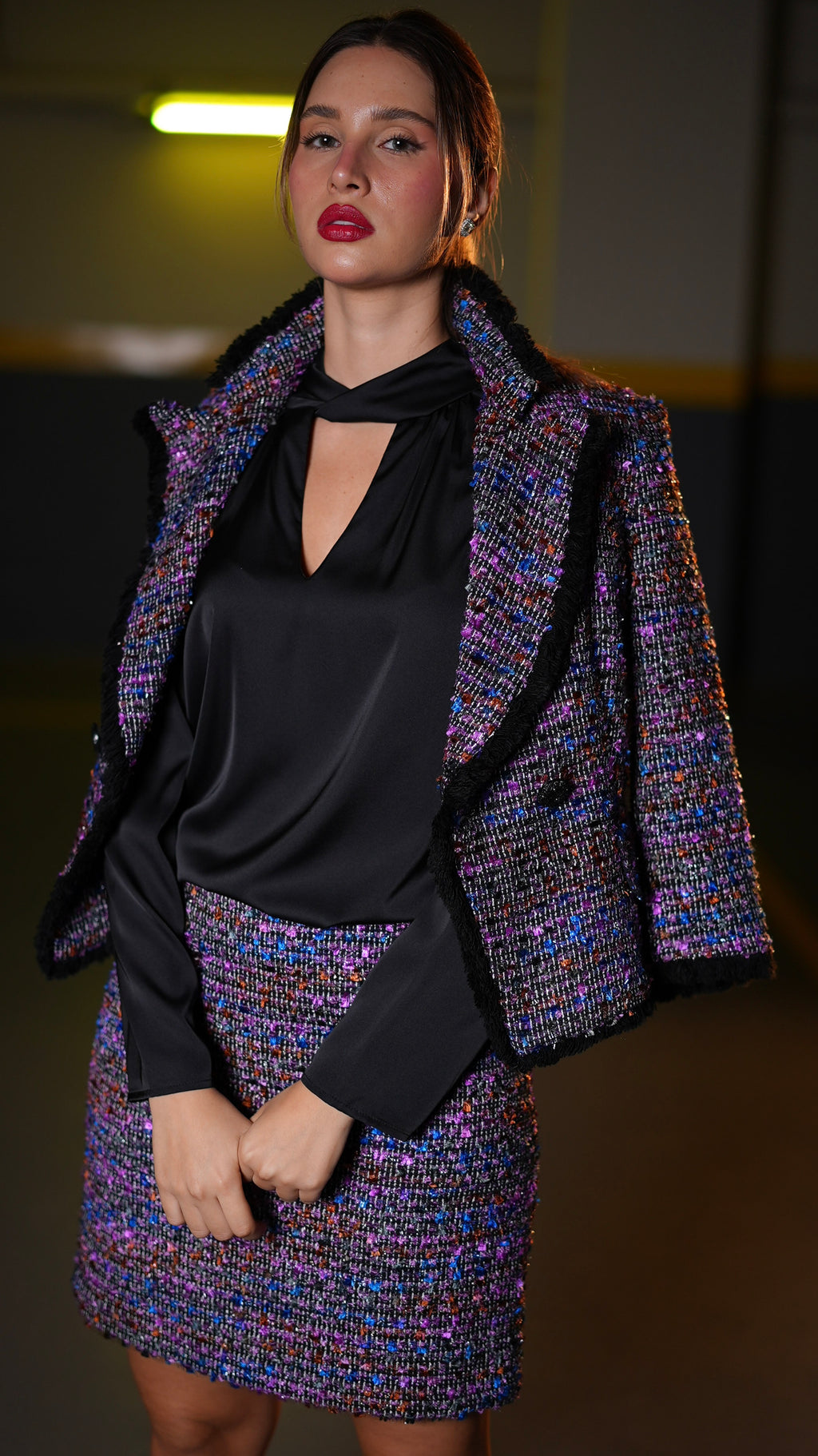 A tweed blazer and mini skirt set in a dark indoor.